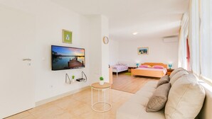 Un soggiorno moderno con una televisione a schermo piatto, un divano, un letto e un'area pranzo.