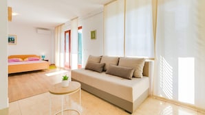 Un soggiorno moderno con un divano, un tavolino tondo e un letto con testiera colorata.