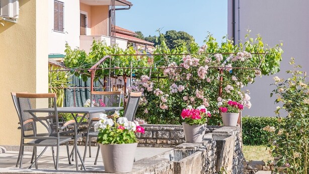 Un patio con mobili da esterno, piante in vaso e un muro in pietra.