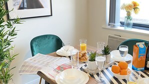 A breakfast table with plates, glasses, and a carton of orange juice. - Tudors eSuites Balcony Apartment (Birmingham)
