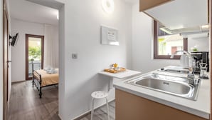 A compact hotel room with a bed, a small kitchenette, a sink, and a view of the outside. - Oroz / Oroz Studio II (Porec)