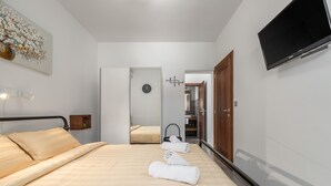 A modern hotel room with a bed, a bedside table, a TV mounted on the wall, and a door leading to a bathroom. - Oroz / Oroz Studio II (Porec)
