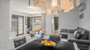 Una sala de estar moderna con una mesa de comedor negra, un sofá gris y un frutero.