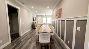 Une longue table à manger avec des chaises, un couloir et une porte.