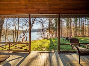 A wooden deck with a view of a lake and forest.