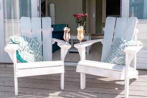 Relax in style with two Adirondack chairs and a serene outdoor setting.