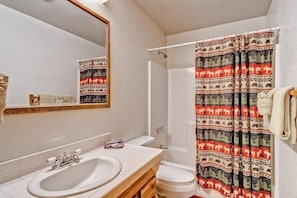 Un baño con lavamanos, inodoro y cortina de ducha con motivos de animales.