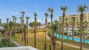 Un resort con piscina, palmeras y un edificio con balcones.
