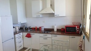 A compact kitchen with white cabinets, a red microwave, and a glass table. - Santa Lina - Magnifique T2 à 200m de la plage (Ajaccio)