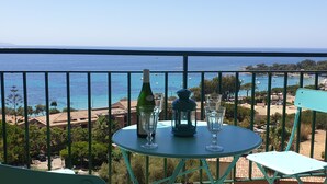A balcony with a table set for two, overlooking a coastal view with boats and buildings. - Santa Lina - Magnifique T2 à 200m de la plage (Ajaccio)