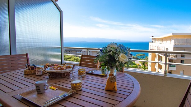 Un balcon avec une table préparée pour le petit-déjeuner, donnant sur la mer.