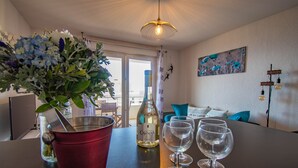 Un coin repas avec une table dressée pour deux personnes, une bouteille de vin et un seau rouge.