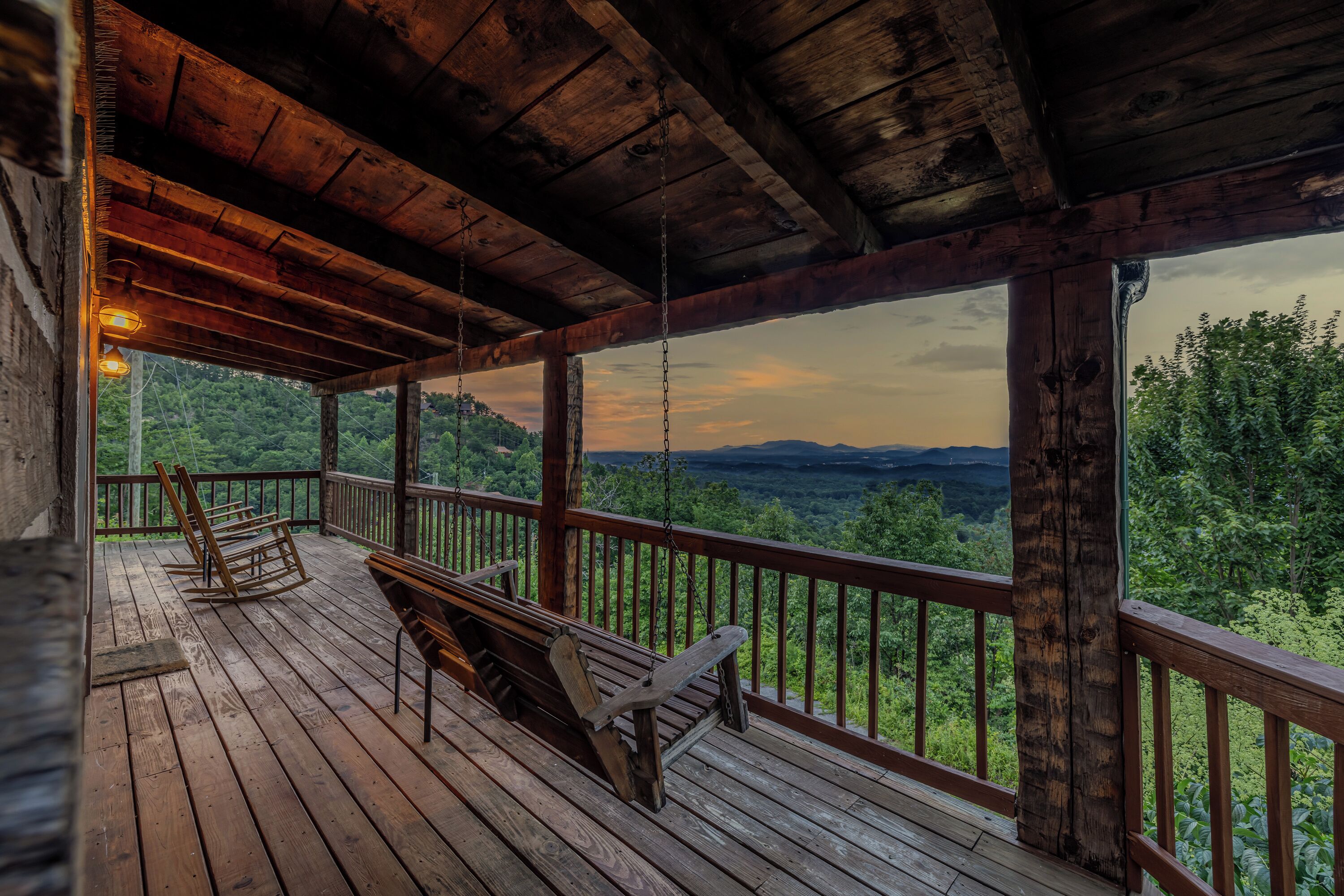 Eine Holzterrasse mit Schaukelstühlen und Blick auf eine gebirgige Landschaft.
