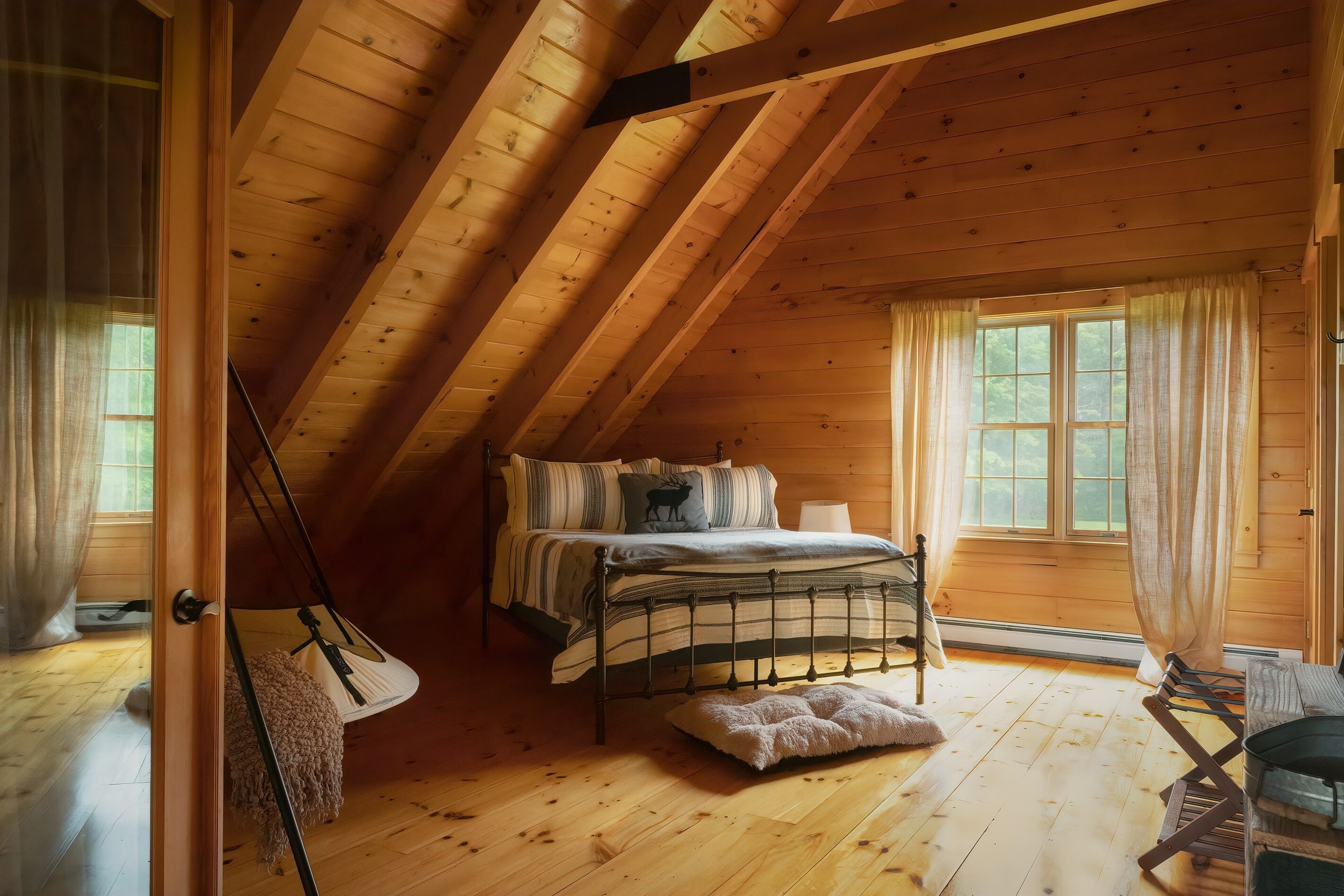 A wooden cabin bedroom with a loft bed, a window with curtains, and a wooden floor.