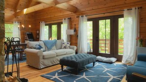 A cozy cabin interior with a sofa, ottoman, and dining table. - Wiggleswick Cottage; Dogs Welcome Certified! 9/17-9/19 available! (Georgetown)