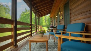 A covered porch with wooden railings, a table with a potted plant, and blue cushioned chairs. - Wiggleswick Cottage; Dogs Welcome Certified! 9/17-9/19 available! (Georgetown)