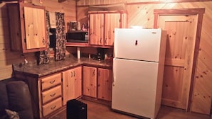 Una cocina compacta con armarios de madera, un refrigerador blanco y un microondas.