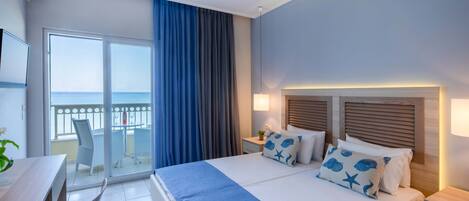 Ein Hotelzimmer mit Bett, Schreibtisch und Balkon mit Meerblick.