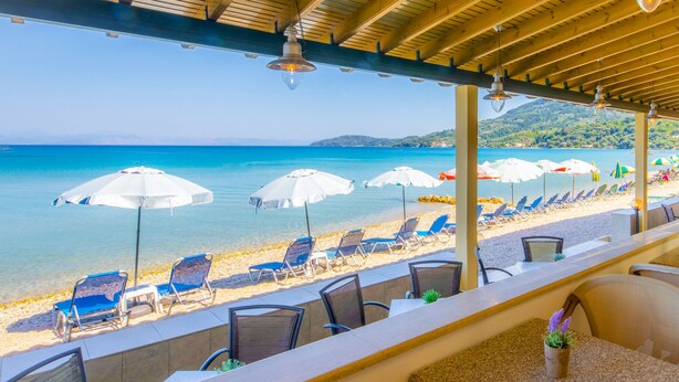 Un bar en la playa con mesas al aire libre y vista al mar azul y transparente.