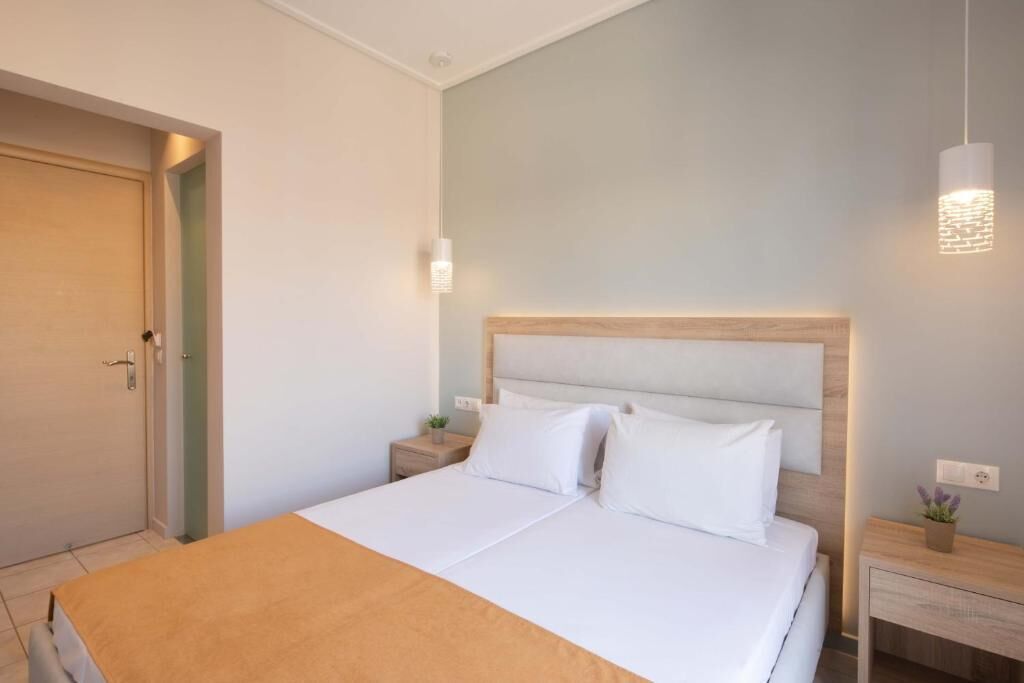 A hotel room with a bed, bedside tables, a nightstand, and a wall-mounted light fixture.