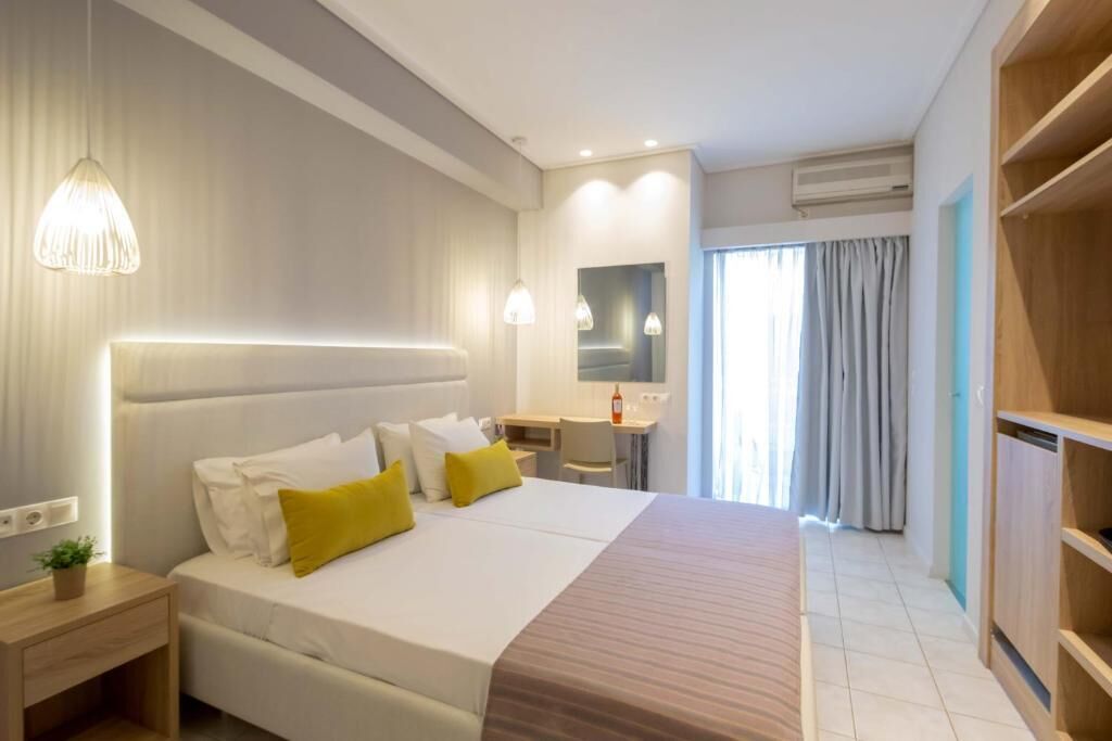 Una habitación de hotel con cama, mesita de noche, escritorio y armario.