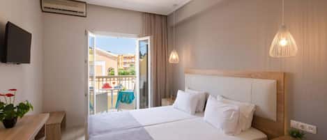 A hotel room with a large bed, a desk, a television, and a balcony with a table and chairs.