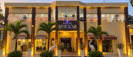 Ein Hotel mit modernem Design, das eine auffällige Eingangspartei mit der Aufschrift 'HOTEL MYTHOLOGIA' zeigt.