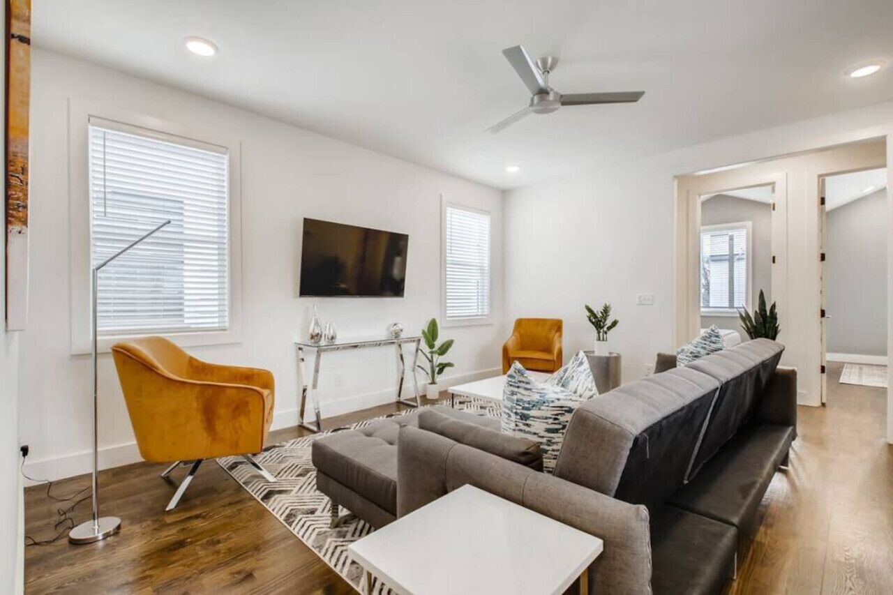 A modern living room with a sofa set, a coffee table, a floor lamp, and a TV mounted on the wall.