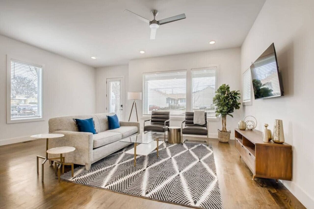 A modern living room with a sofa, two armchairs, a coffee table, and a patterned rug.