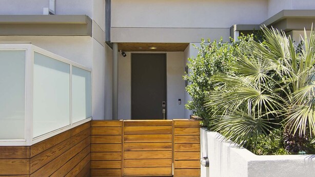 A modern building with a wooden deck, a door, and a small window.