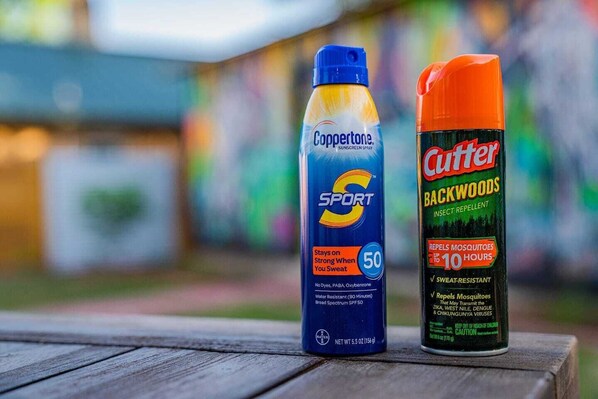 Two bottles of Coppertone sunscreen and Cutter Backwoods insect repellent on a wooden surface.
