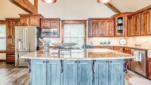 A kitchen with wooden cabinets, a central island, and pendant lighting.