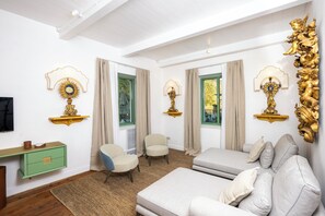 A room with a sofa, chairs, a small table, and decorative wall sconces.