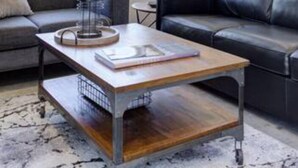 Un salon moderne avec un canapé gris, un divan en cuir noir et une table basse en bois.