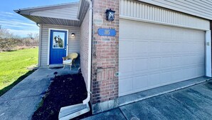Un bâtiment avec un garage, une porte bleue, un mur en briques et un panneau indiquant le numéro de la maison.