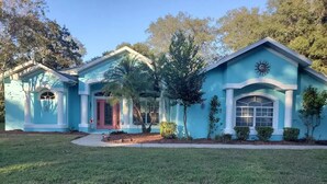 A two-story house with a blue exterior, a red door, and a small front yard. - "Shore Fun, Bare Feet Retreat" (Spring Hill)