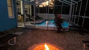A backyard with a fire pit, a pool, and a covered patio area. - "Shore Fun, Bare Feet Retreat" (Spring Hill)