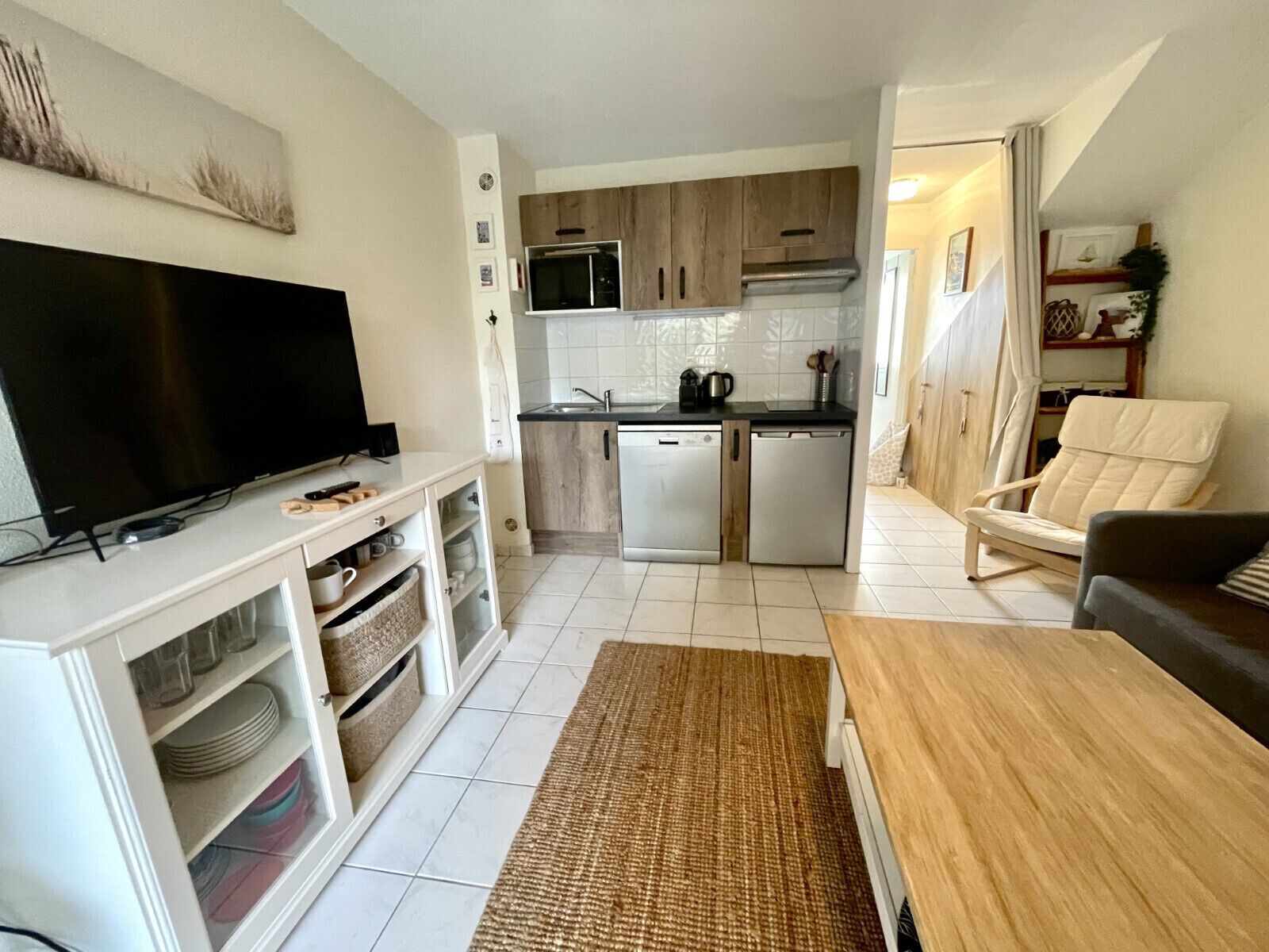 A compact living space with a TV, kitchenette, and seating area.