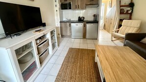 Un espacio habitable pequeño con televisión, kitchenette y zona de estar.