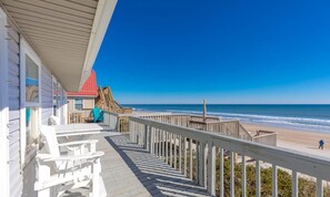 Une terrasse en bois qui mène à une plage et offre une vue dégagée sur l’océan.