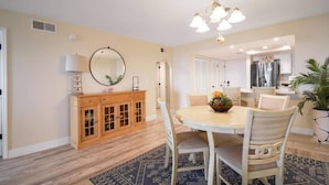 A dining area with a round table, chairs, a chandelier, a wooden cabinet, and a patterned rug. - Oceans Joy (St. Augustine Beach)