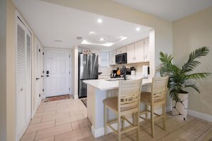 A modern kitchen with a central island, stainless steel appliances, and a potted plant.