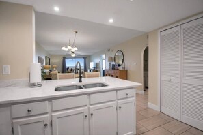 A modern kitchen with a central island, a double sink, and a ceiling fan.