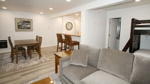 A modern living room with a grey sofa, wooden dining table, and chairs. There is a clock on the wall and a framed picture above the table. - Mammoth Ski & Racquet Club #127 (Mammoth Lakes)