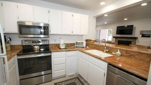 A modern kitchen with stainless steel appliances, white cabinetry, and a granite countertop. - Mammoth Ski & Racquet Club #127 (Mammoth Lakes)
