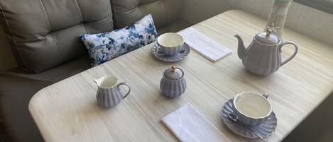 A neatly arranged table with a tea set, a cushion, and a view of the outside.
