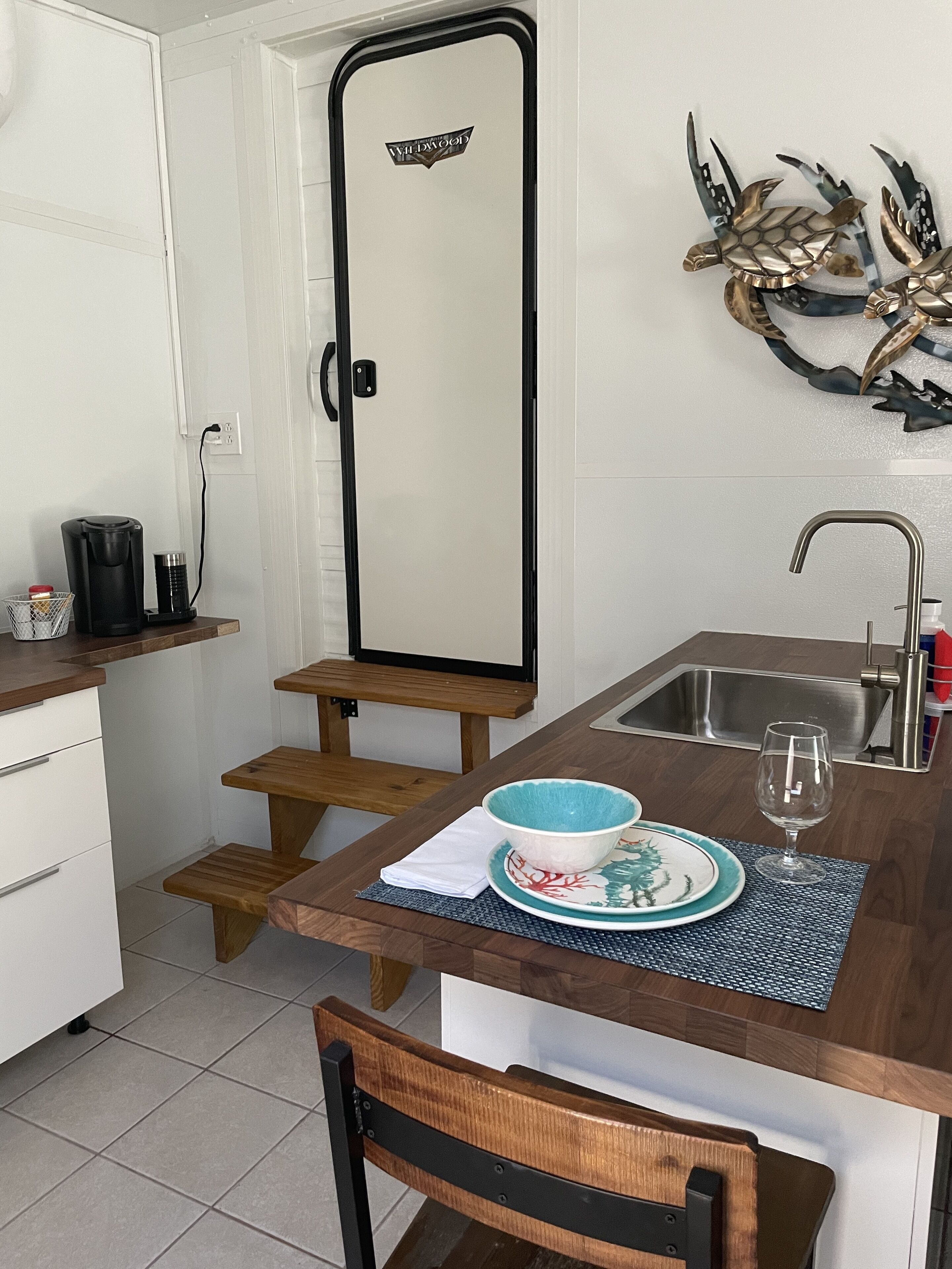 A compact kitchen with a wooden countertop, a sink, and a coffee maker.
