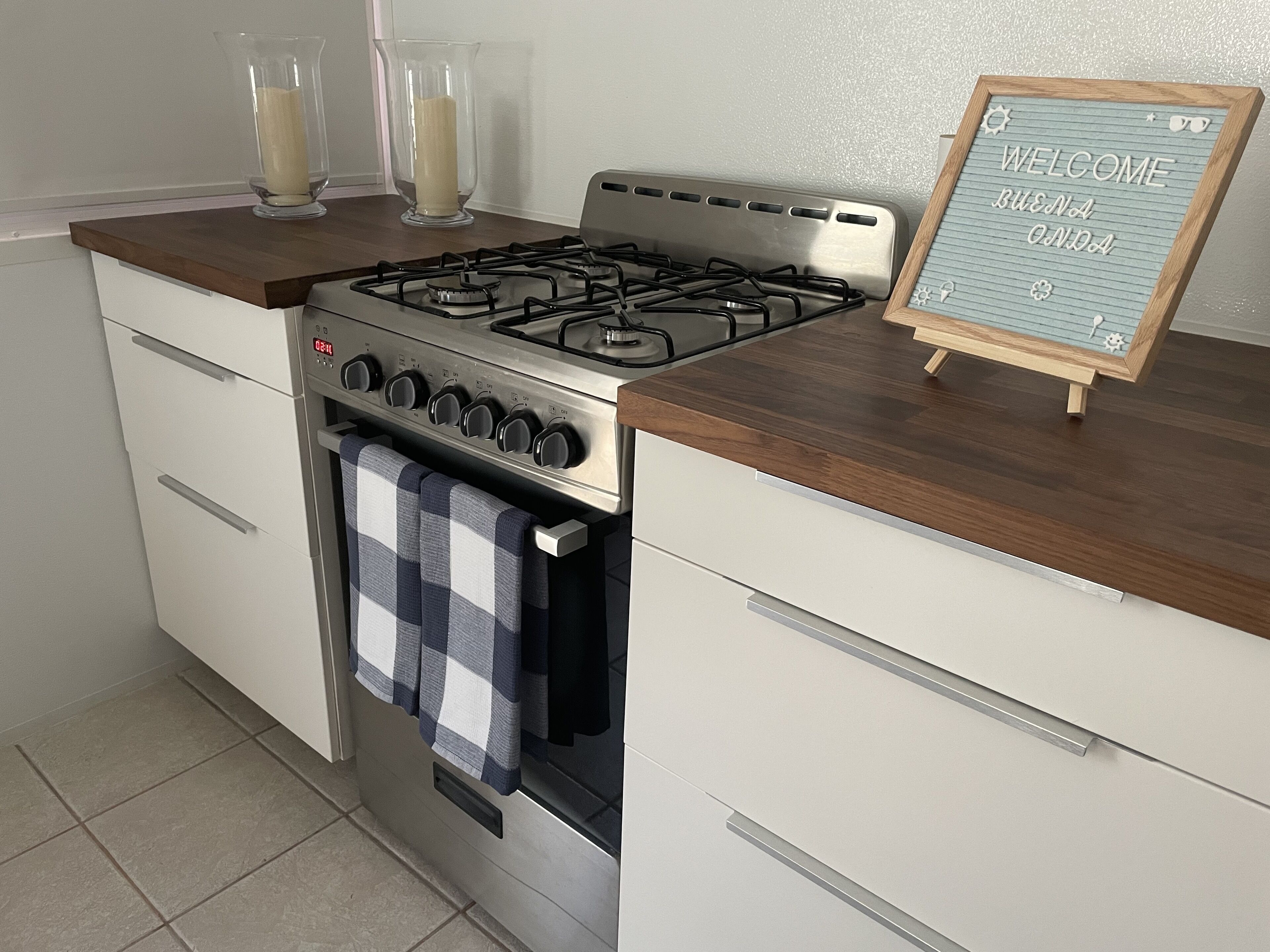 Una cocina con estufa a gas, encimera de madera y un cartel de bienvenida.