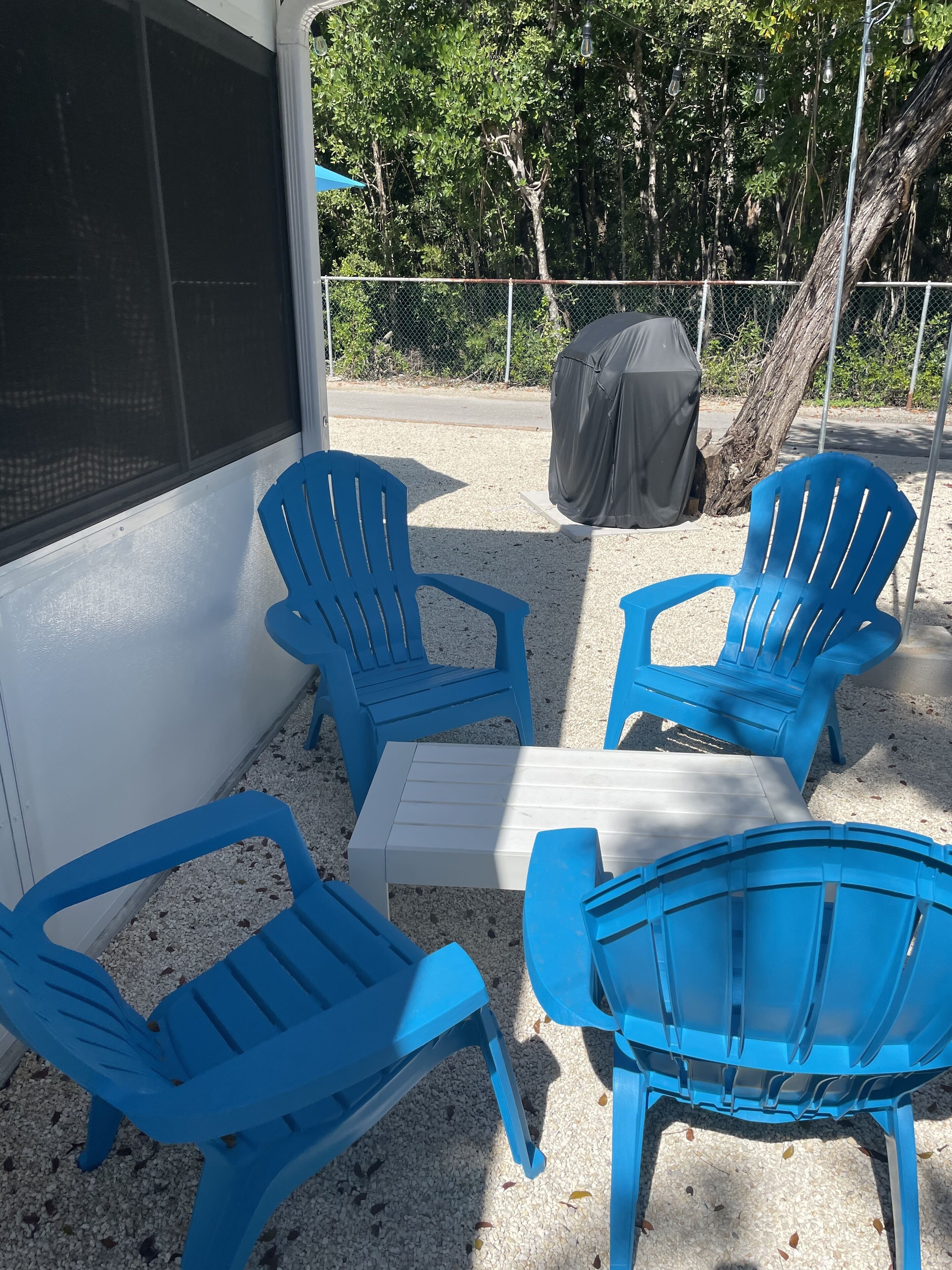 An outdoor seating area with four blue chairs and a small white table.