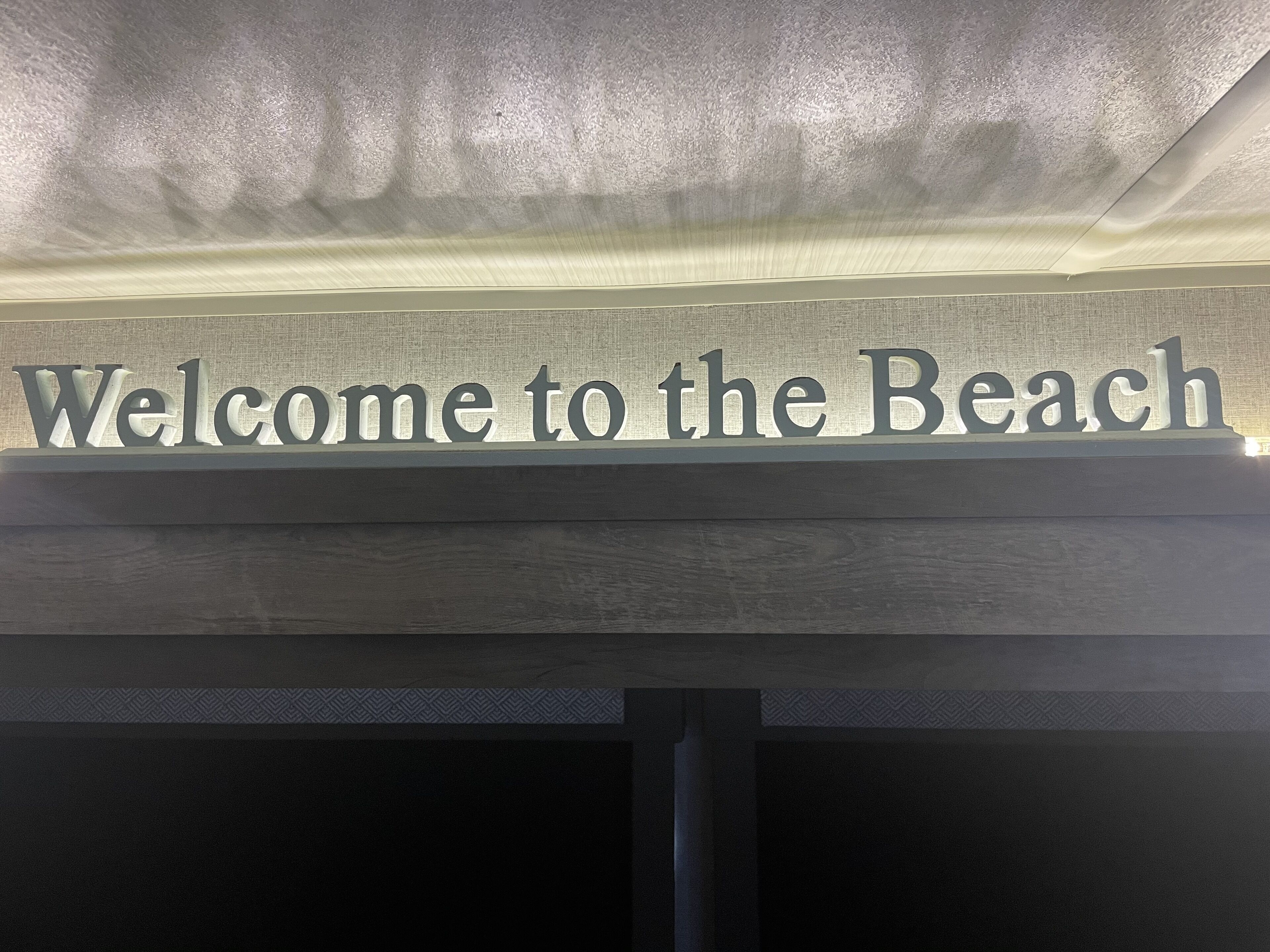 A welcome sign with the text "Welcome to the Beach" in a modern font.
